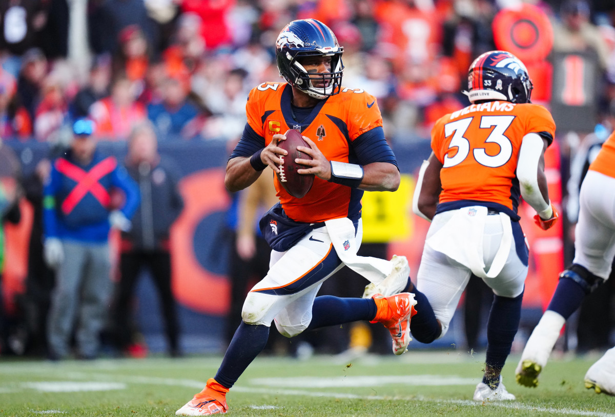Russell Wilson holds the ball in between his two hands while he turns and runs